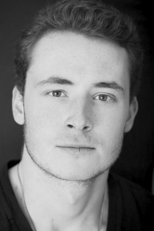 Sam Birch as Suit #2